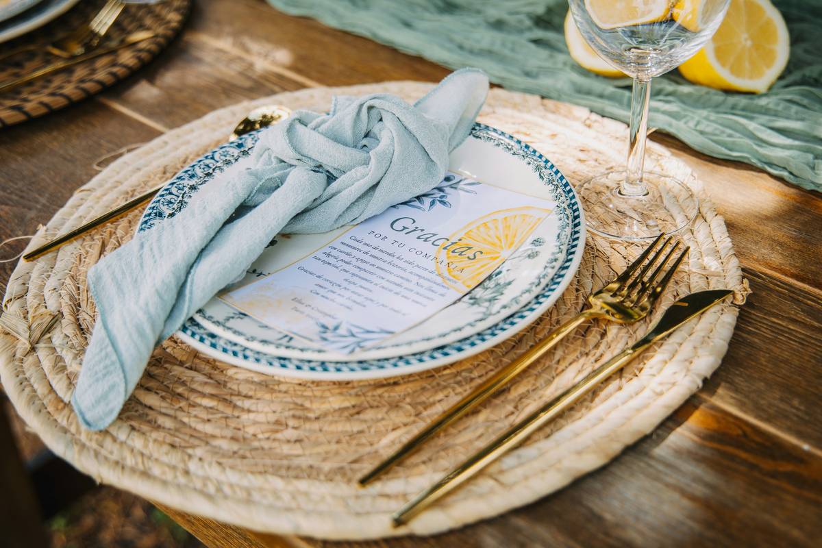 Colorful woven placemats for the table on a wooden dining surface with dinnerware